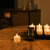 Zes dimbare, oplaadbare LED theelichtjes met een zwarte afstandsbediening (brandtijd 400 uur, waterdicht, timer) staan op een ronde houten tafel in een gezellige, warm verlichte kamer. Een kandelaar en extra kaarsen verschijnen op de achtergrond.
