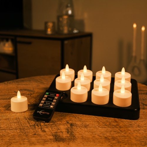 12 waterdichte led waxinelichtjes 2026 met 175 uur brandtijd, waterdicht en voorzien van afstandsbediening en timerfunctie zijn op een zwarte lade gerangschikt, met één kaars apart naast de afstandsbediening op een houten tafel.