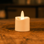 Het LED theelichtje oplaadbaar 175 uur waterdicht warm wit design model IP68 LOS gloeit warm op een houten oppervlak, zijn plastic vlam verlicht de zwak verlichte kamer.