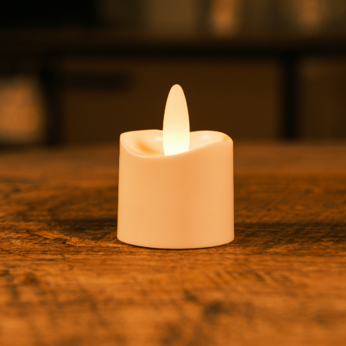 Het LED theelichtje oplaadbaar 175 uur waterdicht warm wit design model IP68 LOS gloeit warm op een houten oppervlak, zijn plastic vlam verlicht de zwak verlichte kamer.