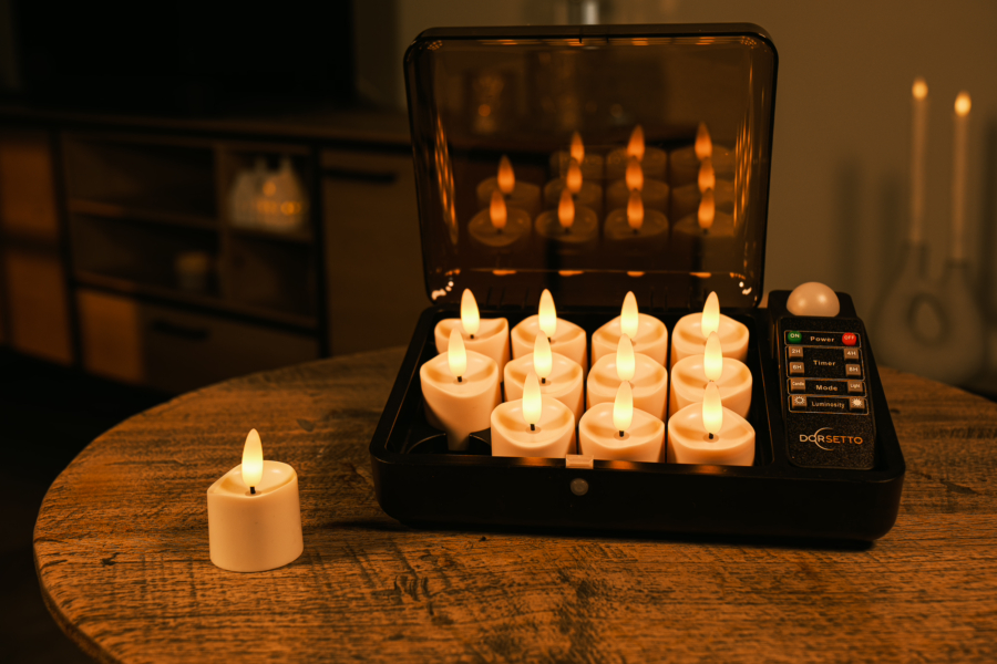 De led waxinelichtjes - tot 400 uur brandduur, 12 stuks, realistisch, met afstandsbediening worden getoond op een houten tafel: elf in een zwart oplaadstation met doorzichtig deksel, één los ernaast. De achtergrond is warm verlicht.