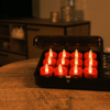 Een set van twaalf oplaadbare waxinelichtjes - tot 400 uur brandduur, realistisch rood LED, waterdicht en met timerfunctie - wordt getoond in een zwarte oplaadkoffer op een houten tafel, met afstandsbediening en zachte woonkamerverlichting.