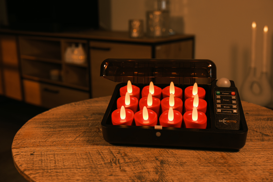 Een set van twaalf oplaadbare waxinelichtjes - tot 400 uur brandduur, realistisch rood LED, waterdicht en met timerfunctie - wordt getoond in een zwarte oplaadkoffer op een houten tafel, met afstandsbediening en zachte woonkamerverlichting.