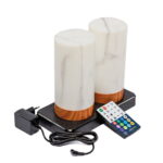 Twee waterdichte, oplaadbare LED tafellampen in cilindervorm met marmer wit en hout look, inclusief timerfunctie, worden geleverd met een zwarte oplaadbasis, afstandsbediening en voedingsadapter met snoer.