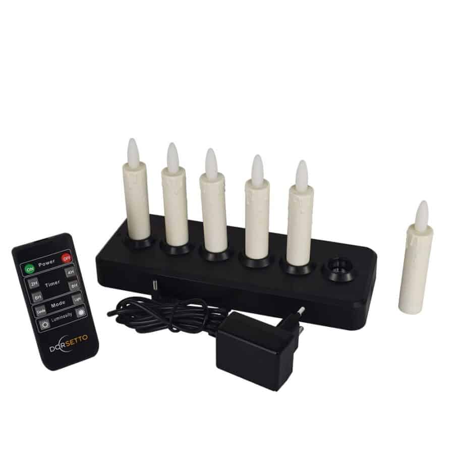 Zes oplaadbare ivoorkleurige dinerkaarsen (97 mm, warm wit, 130 uur brandtijd), een zwarte oplaadbasis, voedingsadapter en Dorsetto-afstandsbediening worden afgebeeld op een witte achtergrond. Eén kaars staat niet op de oplaadbasis.
