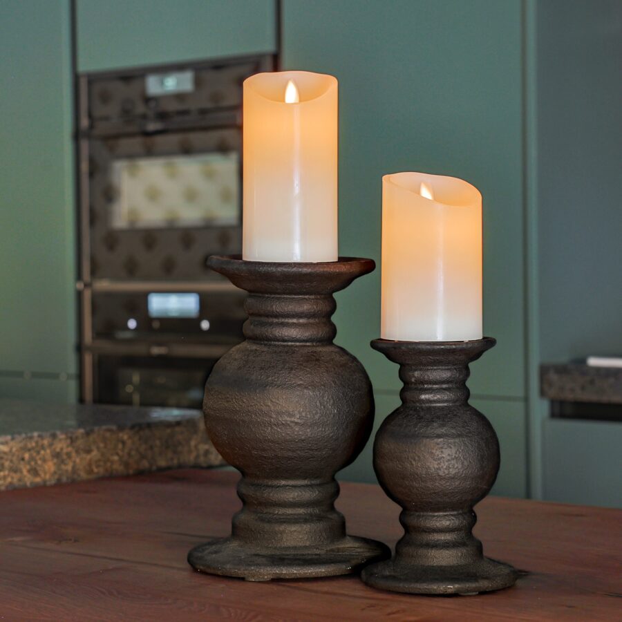 Twee oplaadbare led kaarsen (set van 2, 30 uur brandtijd, timerfunctie, afstandsbediening, klein) staan op donkere houten houders op een houten oppervlak in een moderne keuken met groene kasten en een oven.