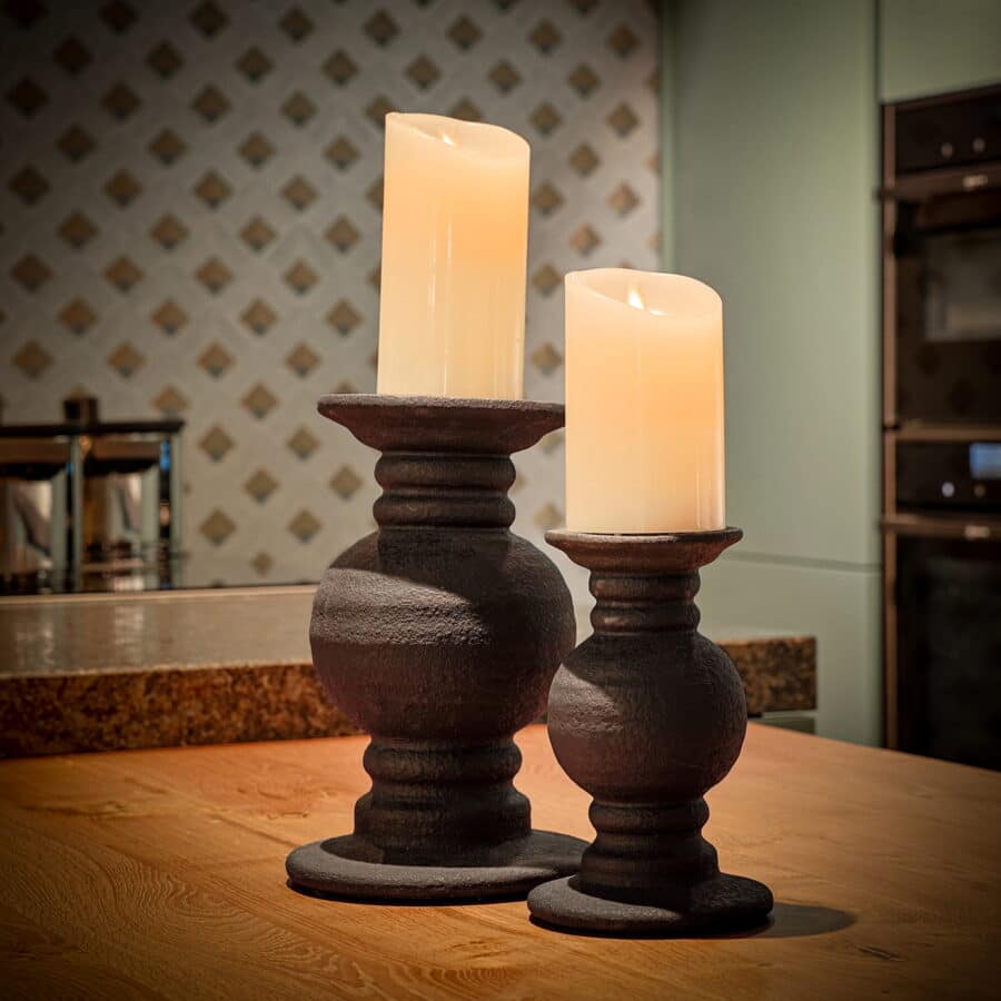Twee Oplaadbare led kaarsen (7,5cm x 12,5cm, 30 uur brandtijd, afstandsbediening) gloeien op donkere kaarsenhouders bovenop een houten aanrecht in een warm verlichte keuken met gedessineerde achterwand en moderne apparatuur.