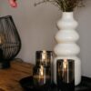 Een witte vaas van keramiek met rode en crèmekleurige bloemen staat op een houten tafel naast drie donkergrijze oplaadbare ledkaarsen (3 oplaadbare ledkaarsen, met afstandsbediening, 105 uur brandtijd) gerangschikt op een rond zwart dienblad.
