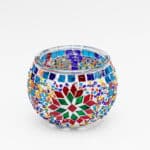 Theelichthouder vrolijke 9 CM DORSETTO is een ronde glazen kandelaar met kleurrijke mozaïeksteentjes en kralen, waardoor geometrische en bloempatronen ontstaan in rood, groen, blauw, geel, oranje en paars op wit.