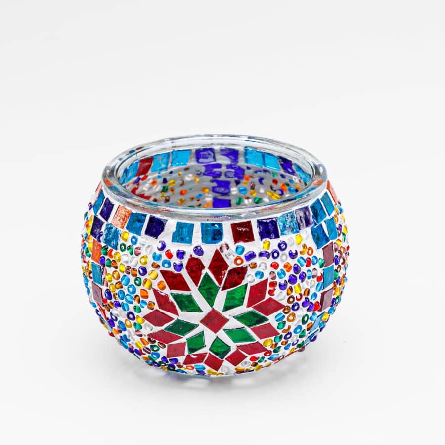 Theelichthouder vrolijke 9 CM DORSETTO is een ronde glazen kandelaar met kleurrijke mozaïeksteentjes en kralen, waardoor geometrische en bloempatronen ontstaan in rood, groen, blauw, geel, oranje en paars op wit.