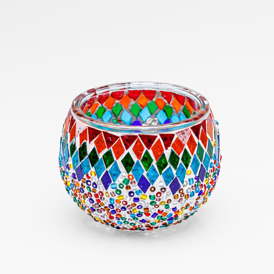 Theelichthouder gekleurde spikkels 9 CM DORSETTO: een ronde glazen waxinelichthouder met kleurrijke kralen- en mozaïekpatronen in rood, blauw, groen, oranje en geel op een witte achtergrond.