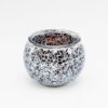 De Theelichthouder zwart 9 CM DORSETTO is een ronde glazen theelichthouder met een zwart mozaïekdesign, voorzien van reflecterende, onregelmatige stukjes glas en een metalen rand. Het glanzende, gefragmenteerde patroon steekt af tegen een effen witte achtergrond.