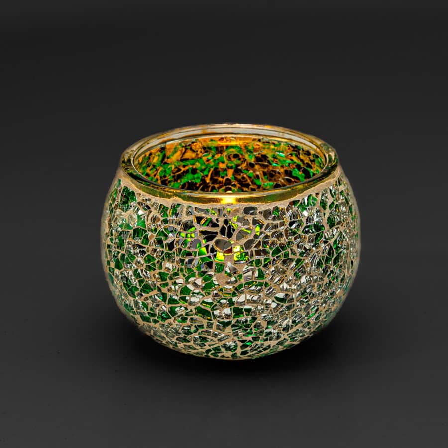 Theelichthouder DORSETTO 9 cm donker groen: een ronde glazen kandelaar met een mozaïek van groene en gouden stukjes tegen een effen zwarte achtergrond.