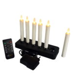 Zes oplaadbare dinerkaarsen (150mm, warm wit, 58u brandtijd) staan in een zwarte oplader; één kaars staat ernaast. Afstandsbediening en adapter zijn ook afgebeeld.