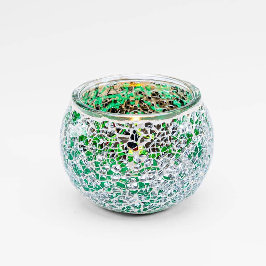 Theelichthouder DORSETTO 9 cm donker groen is een ronde glazen kandelaar met groene, witte en zilveren mozaïektegeltjes in een sprankelend patroon. De lege houder is afgebeeld tegen een effen witte achtergrond.