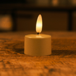 Een Led theelichtje Jitney No.293 beige met tot 250 uur merkduur staat op een houten oppervlak en zorgt voor een warme, gezellige sfeer in de kamer.