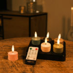 Zes kleurrijke oplaadbare led waxinelichtjes met een brandduur tot 400 uur staan uitgestald op een dienblad; een afstandsbediening van Dorsetio ligt vooraan en een roze kaars staat apart aan de linkerkant.