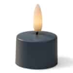 Een klein, donkerblauw, cilindervormig LED waxinelichtje met een realistisch, vlamvormig licht bovenop, tegen een witte achtergrond.